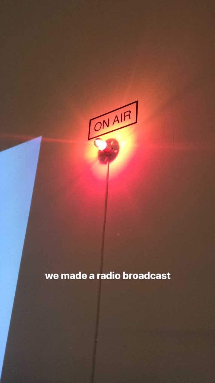 A lit red light on the wall labelled On Air